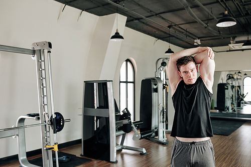 Fit strong young man stretching arms and  when getting ready to work out in gym