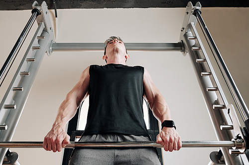 Strong fit young man lifting heavy weights in gym