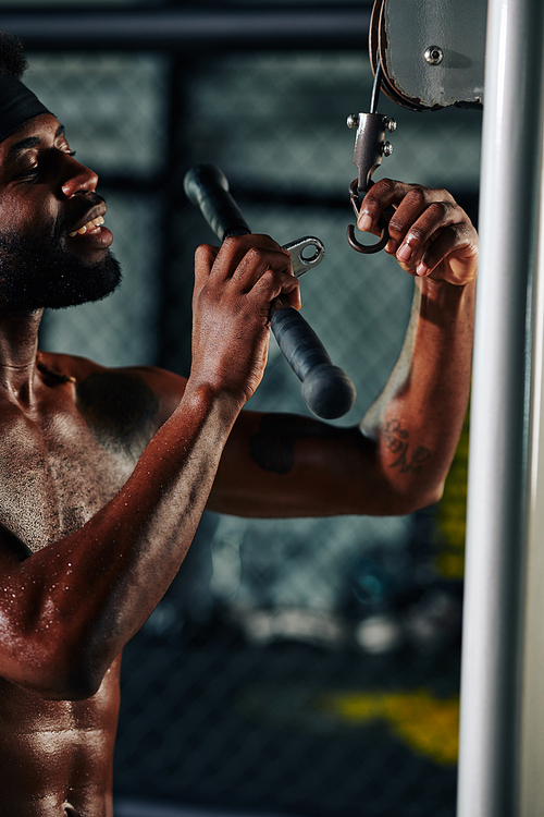 African American man standing topless changing fitness machine bar vertical shot