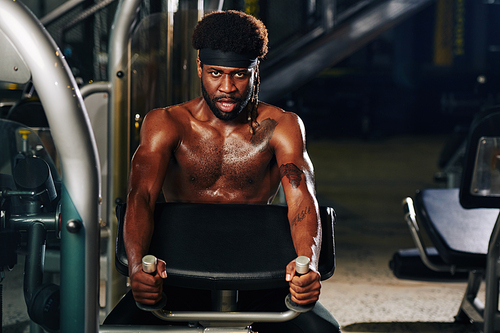 Horizontal portrait of serious sportsman doing strengthening exercise in gym 