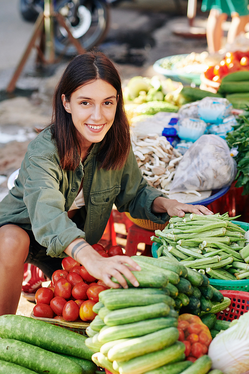 Portrait of cheerful Caucasian woman choosing fresh vegetables at farmer's market  smiling