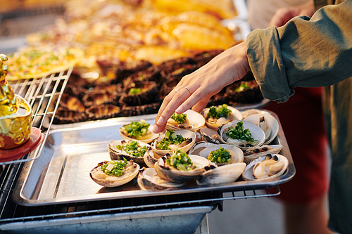 Unrecognizable woman choosing tasty shellfish at Assian street food market, horizontal shot