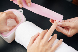 Manicurist asking client to put one hand in soaking bowl when filing nails on other hand