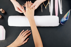 Manicurist massaging hand of female client with nourishing cream, view from above