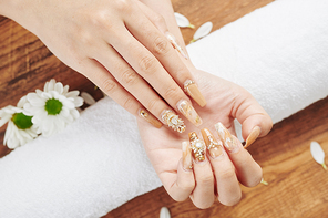 Woman showing her fancy creative manicure with golden polish and jewelry rhinestones