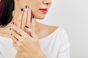 Young beautiful woman touching her face with well-groomed hands with blue nail polish