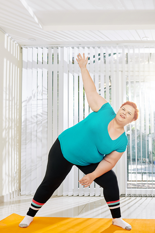Happy young overweight woman attending fitness class in heath club
