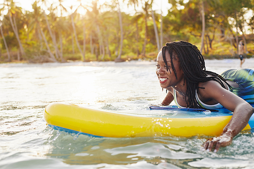 Joyful excited young woman surfing in the ocean