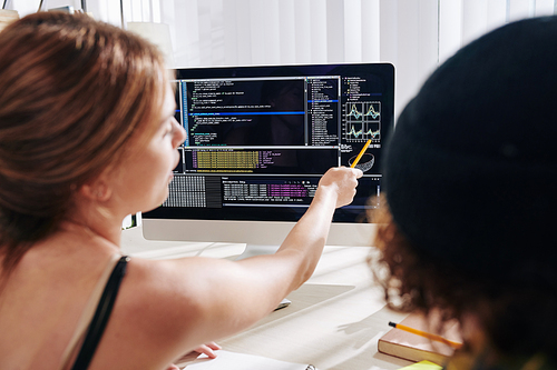 Teenagers studying programming at home and discussing generated chart on computer screen, view from the back