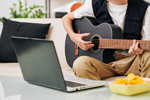 Cropped image of creative teenage boy playing guitar and writing new song