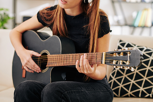 Cropped image of talented teenage girl singing and playing guitar