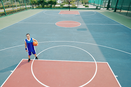 Young woman playing alone on outdoor basketball court