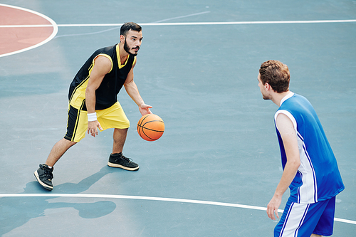 Multi-ethnic young men playing basketball on outdoor court