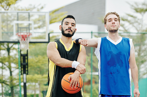 Tired sweaty basketball players standing on outdoor court after playing game