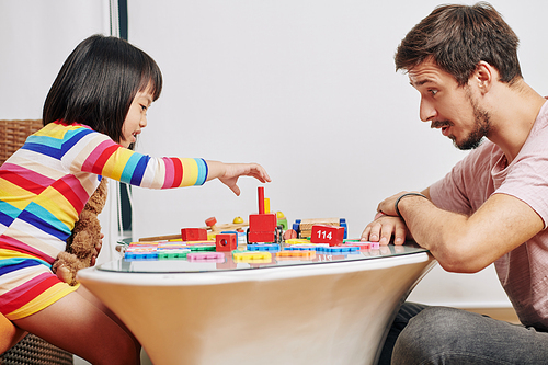 Young father and daughter enjoying playing with colorful wooden blocks