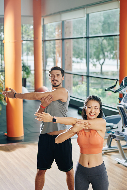Happy young multi-ethnic couple warming up and doing exercise for arm stretch
