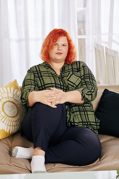 Portrait of young overweight woman resting on sofa at home