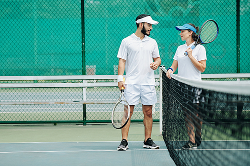 Multi-ethnic couple discussing game after playing tennis outdoors