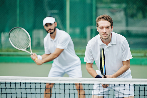 Doubles team of tennis players in white sportswear ready to hit the ball