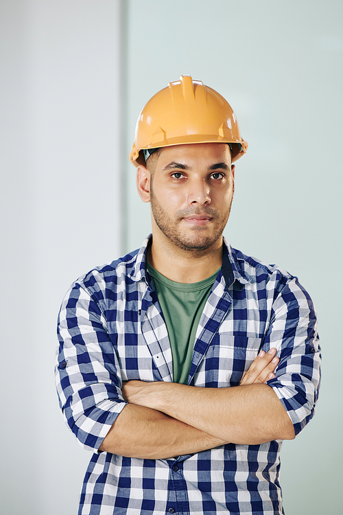 Waist up portrait shot of modern construction worker wearing checked shirt and protective hardhat standing with arms crossed