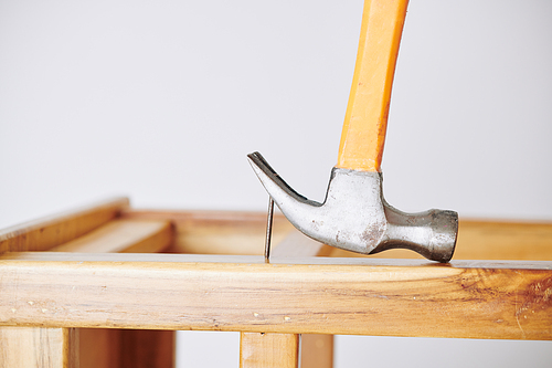 Close-up image of builder using hammer to pull nail out of wooden board