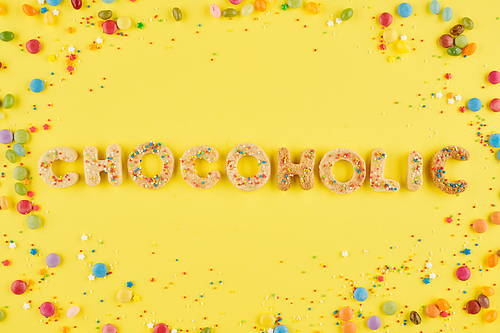 Chocoholic word made of sweet cookies decorated with colorful sprinkles and chocolate candies around