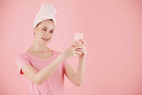 Young smiling attractive woman takig selfie after morning shower or recording video for subscribers