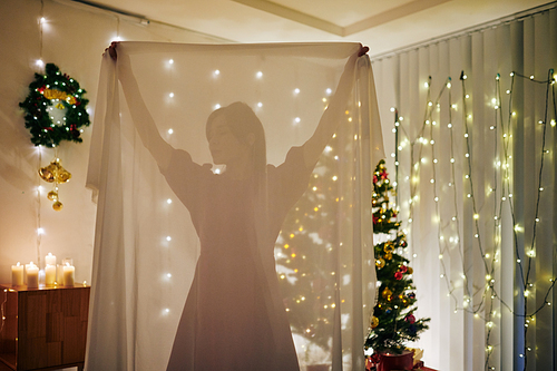 Young woman taking transparent table cloth when decorating room for Christmas celebration