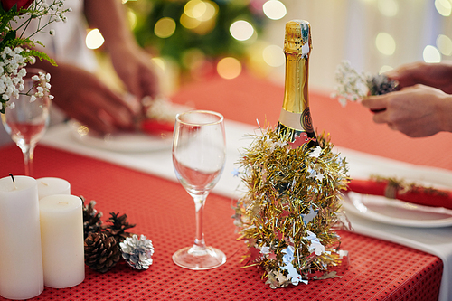 Champagne bottle decorated with tinsel on Christmas dinner table