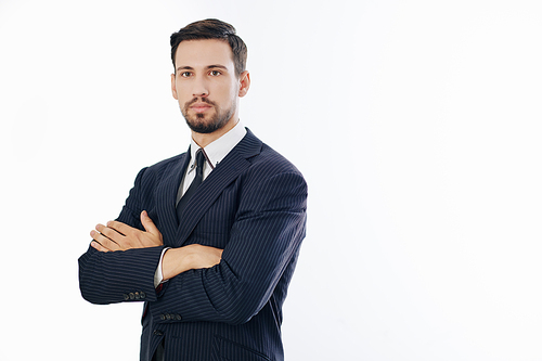 Studio portrait of serious young handsome confident entrepreneur folding arms and looking at camera