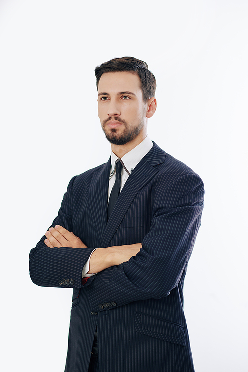 Studio portrait of confident young entrepreneur standing with arms crossed