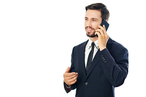 Handsome young businessman in suit smiling when talking on phone with colleague or client