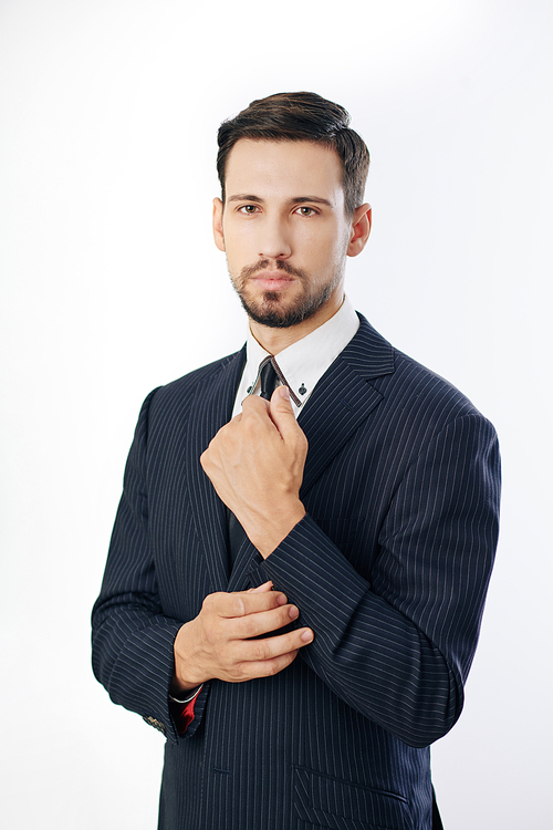 Portrait of confident serious entrepreneur adjusting sleeve and looking at camera, isolated on white