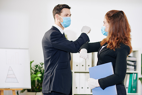 Business people in medical masks and rubber gloves doing elbow bump due to coronavirus pandemic when greeting each other before meeting