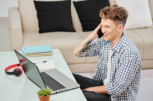 Happy laughing high school student staying at home during lockdown and talking on phone with teacher or friend