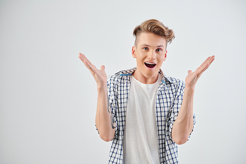 Studio portrait of happy excited or shocked teenager opening mouth and raising arms