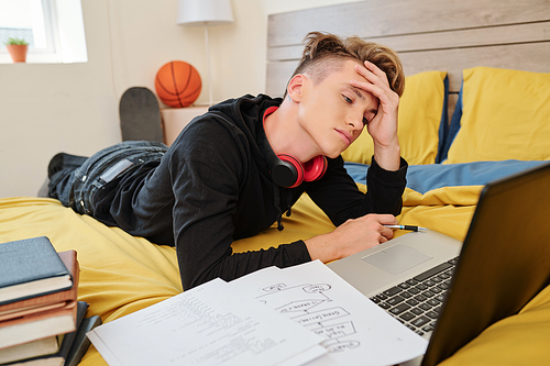 College software engineering student watching webinar on difficult topic online when lying on bed in dormitory