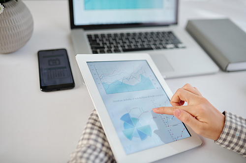 Close-up image of businesswoman checking diagram on screen of digital tablet when working at office desk