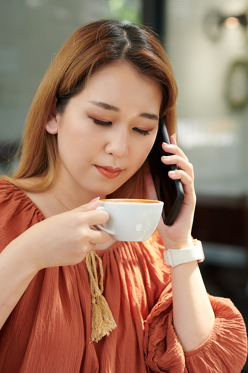Portrait of woman drinking morning coffee and talking on phone