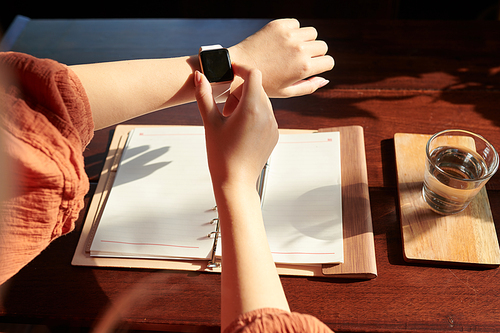 Hands of female entrepreneur checking time or notifications on smartwatch