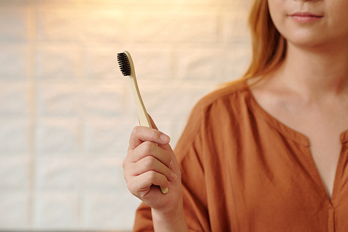 Young woman showing environmentally friendly wooden toothbrush