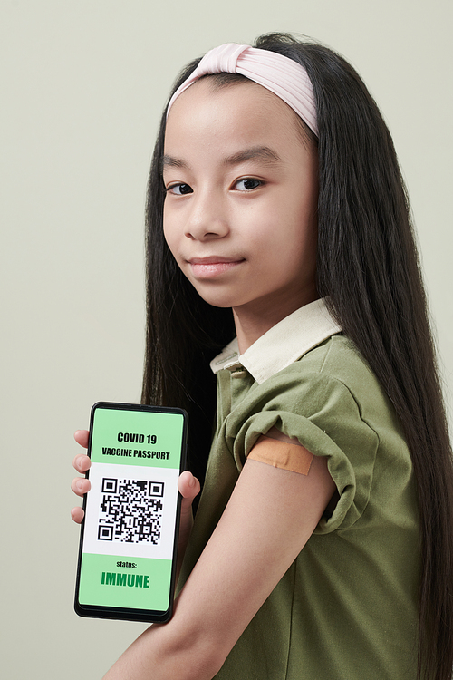 Girl showing smartphone with QR code on the screen that links to COVID 19 vaccination passport