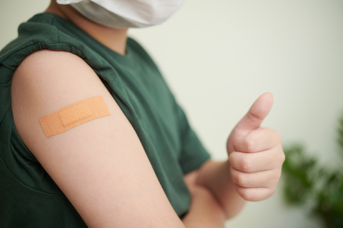 Close-up image of adhesive plaster on shoulder of little boy who was vaccinated against coronavirus