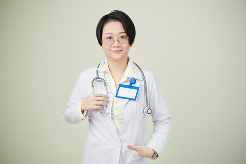 Portrait of positive smiling female general practitioner with badge and stethoscope