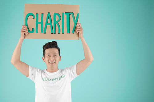 Portrait of handsome young Asian man with placard promoting charity event