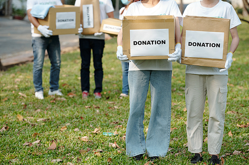 Cropped image of volunteers holding boxes with clothes donated for homeless shelter