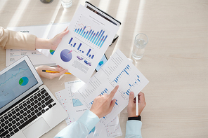 Hands of business people analyzing information in reports and making conclusion on company performance