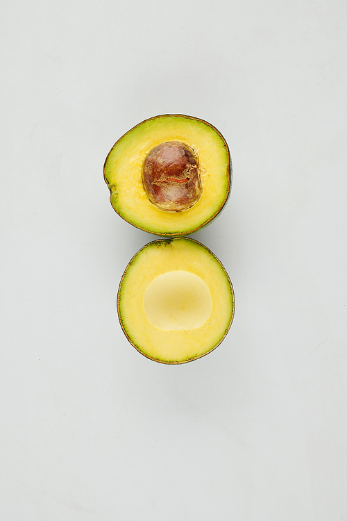 Delicous cut avocado on grey background with core inside, view from above