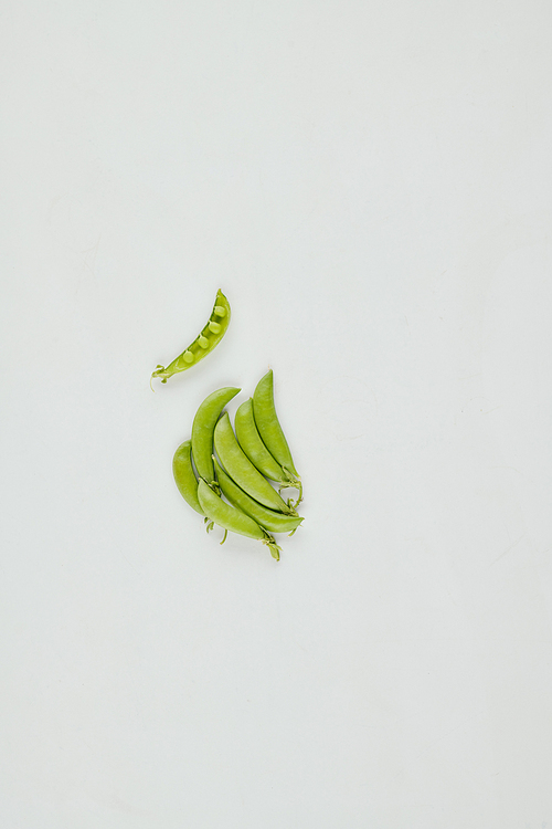 Small pile of green peas in pods on grey background, healthy eating and fiber and antioxidants source concept