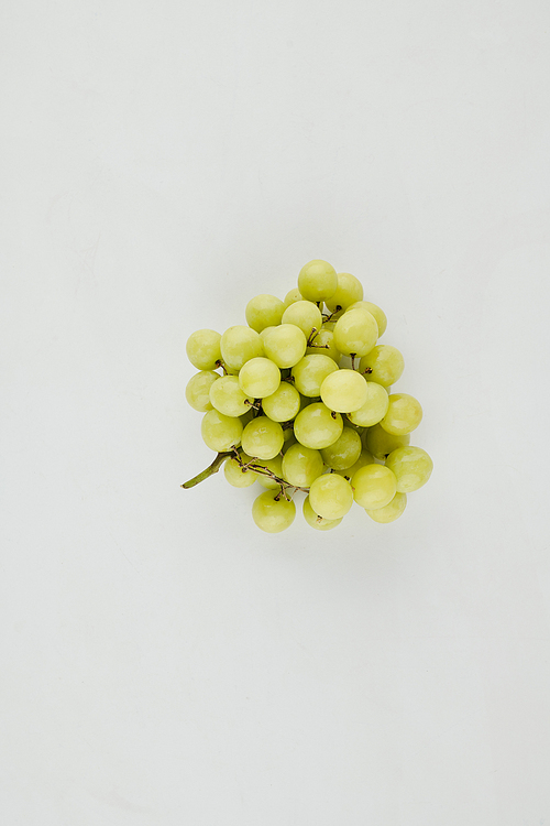 Cluster of green grapes on light grey surface, healthy snack concept